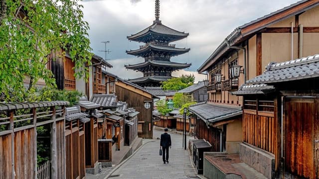 Traveler walking along a traditional street in Kyoto, Japan, with a pagoda in the distance